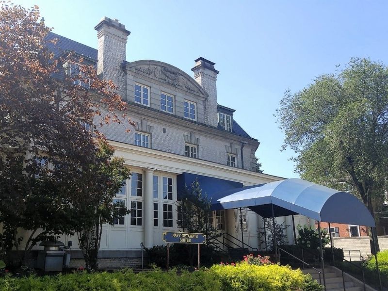 A stately building with a blue awning over the stair leading to the entrance