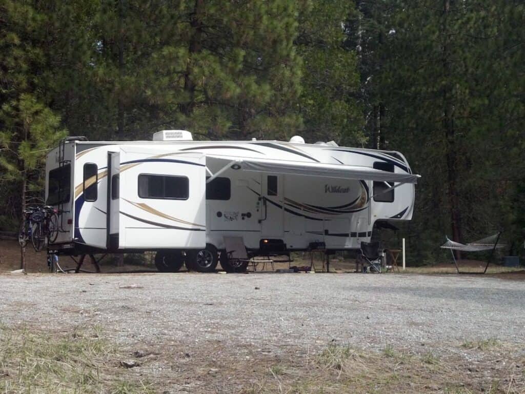 An RV in a clearing surrounded by trees