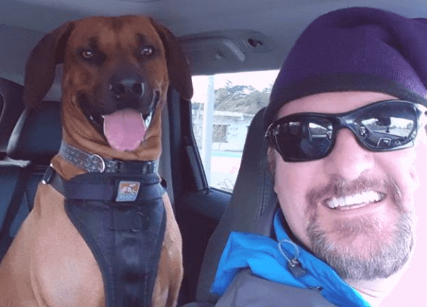 Picture of the author wearing a winter hat sitting in the car with his dog.