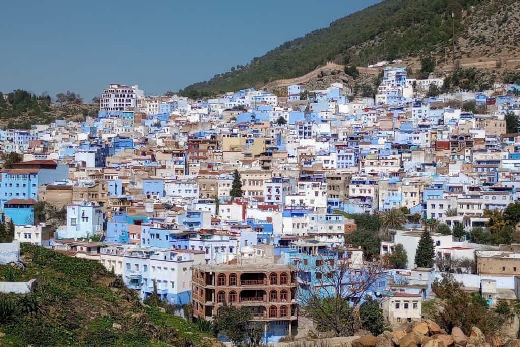 A mountainside town full of buildings painted light blue