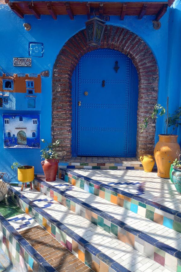 A bright blue door with colorful tile steps leading up to it