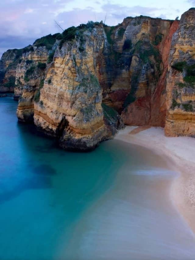 Towering cliff above a beach with turquoise water