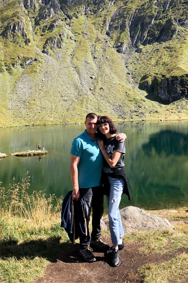 A man and woman standing in front of a lake