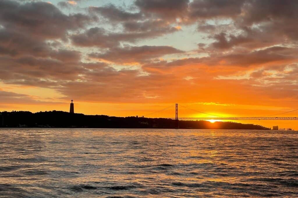 Sunset behind a suspension bridge and statue