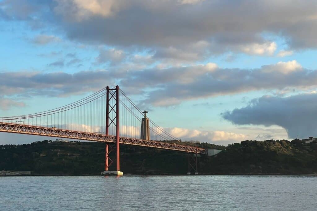 A suspension bridge with a statue of Christ in the background