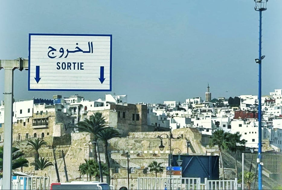 Ferry terminal exit sign with the skyline of Tangier behind it